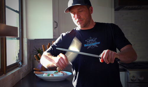Chef Adam Glick honing a knife on a steel in a kitchen