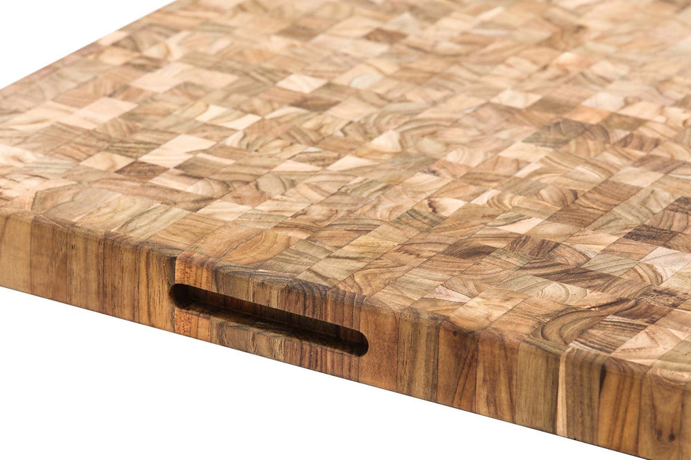 Close-up of a rectangular wooden cutting board made from a checkered wood block pattern, featuring a built-in handle cutout on one side, set against a plain white background.