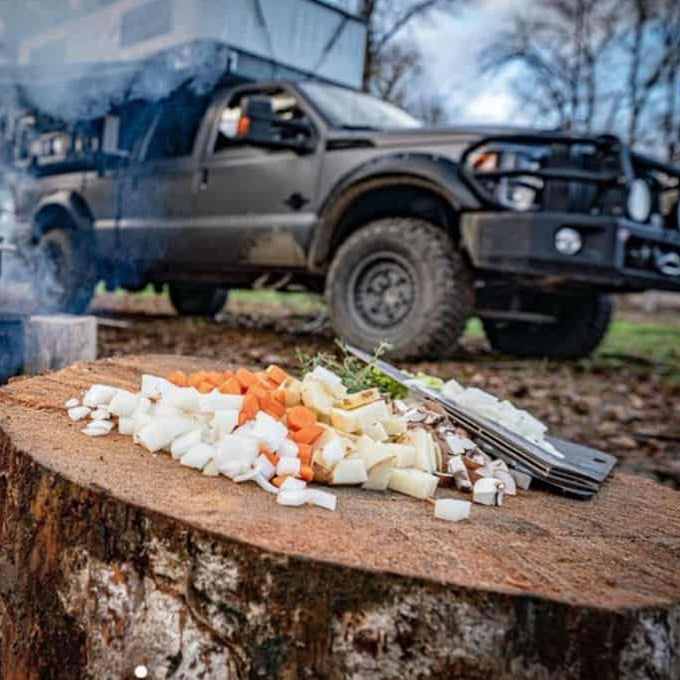 Prepared food on a wooden stump with an off-road vehicle in the background