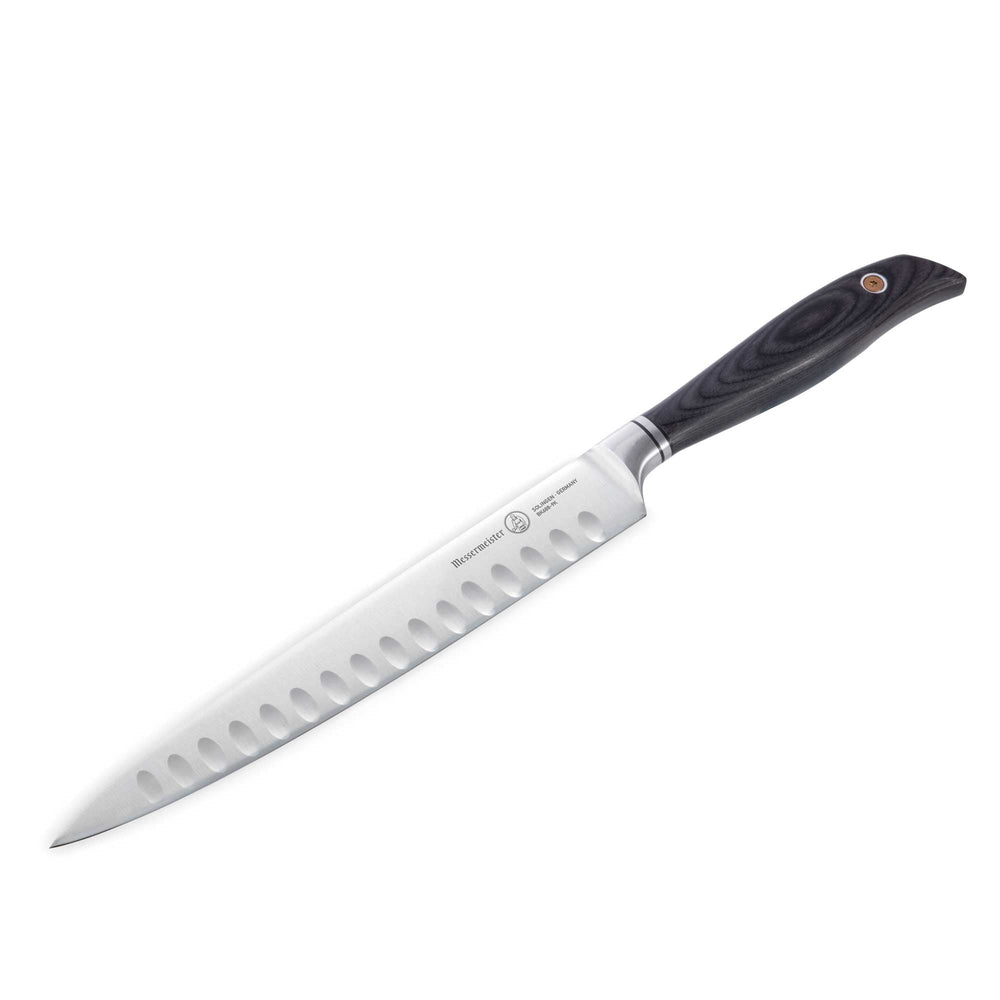 Messermeister Blacksmith 9-Inch Kullens Carving Knife with a long hammered high-carbon stainless steel blade and kullens granton edge, positioned at an angle to showcase the razor-sharp slicing edge and ebony pakkawood handle