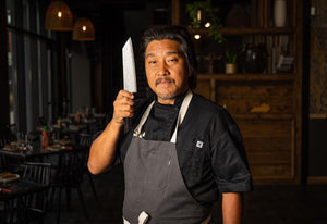 Chef Edward Lee holding his knife in a restaurant setting