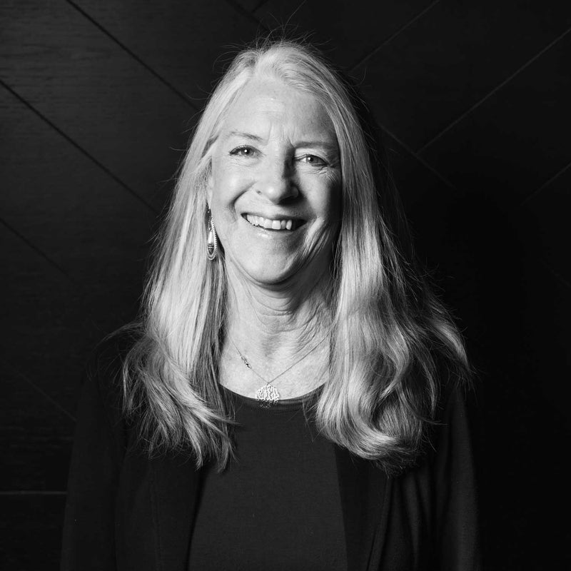 Black and white portrait of Debra Dressler with gray hair against a dark background