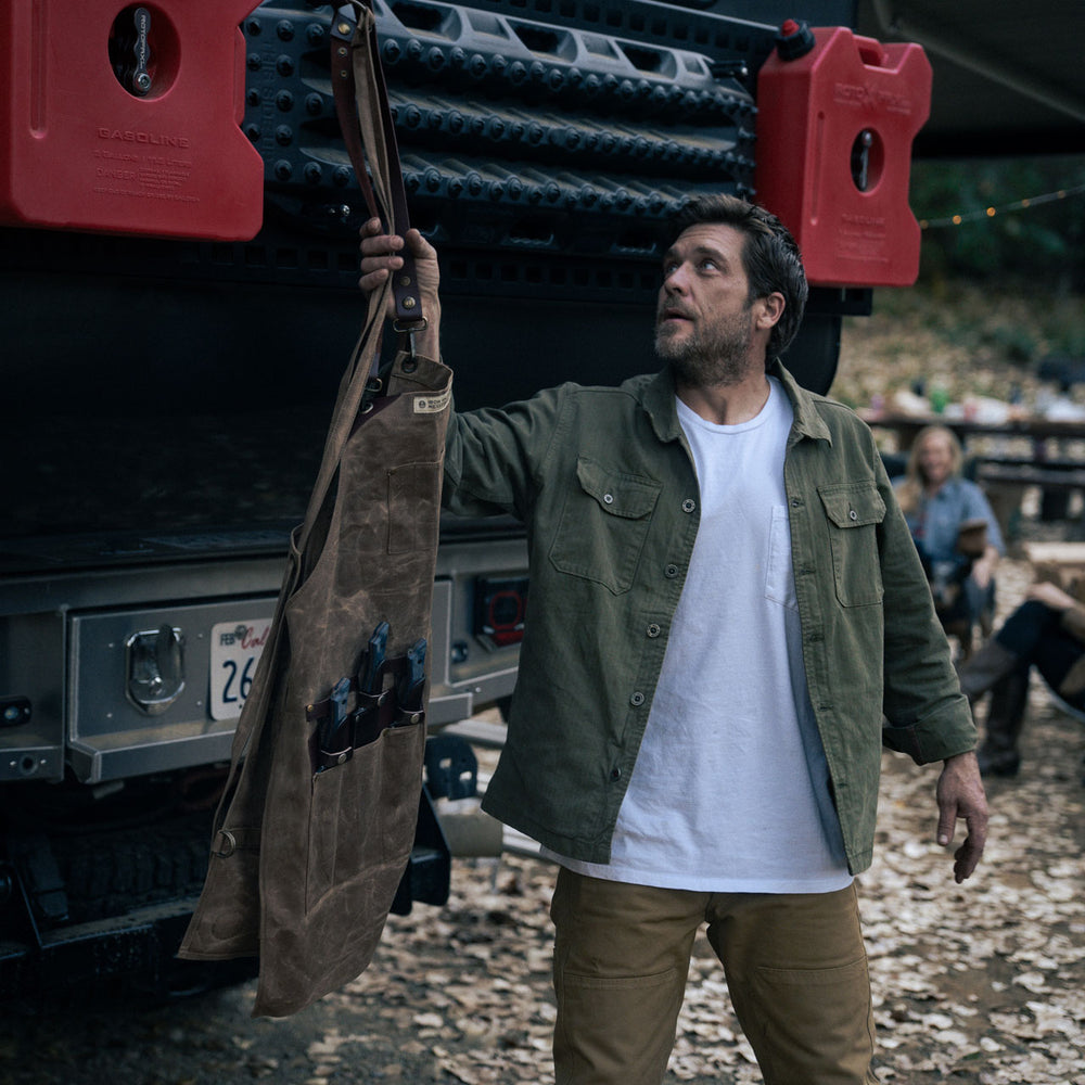 man hanging up the brown leather apron up on the back of a truck