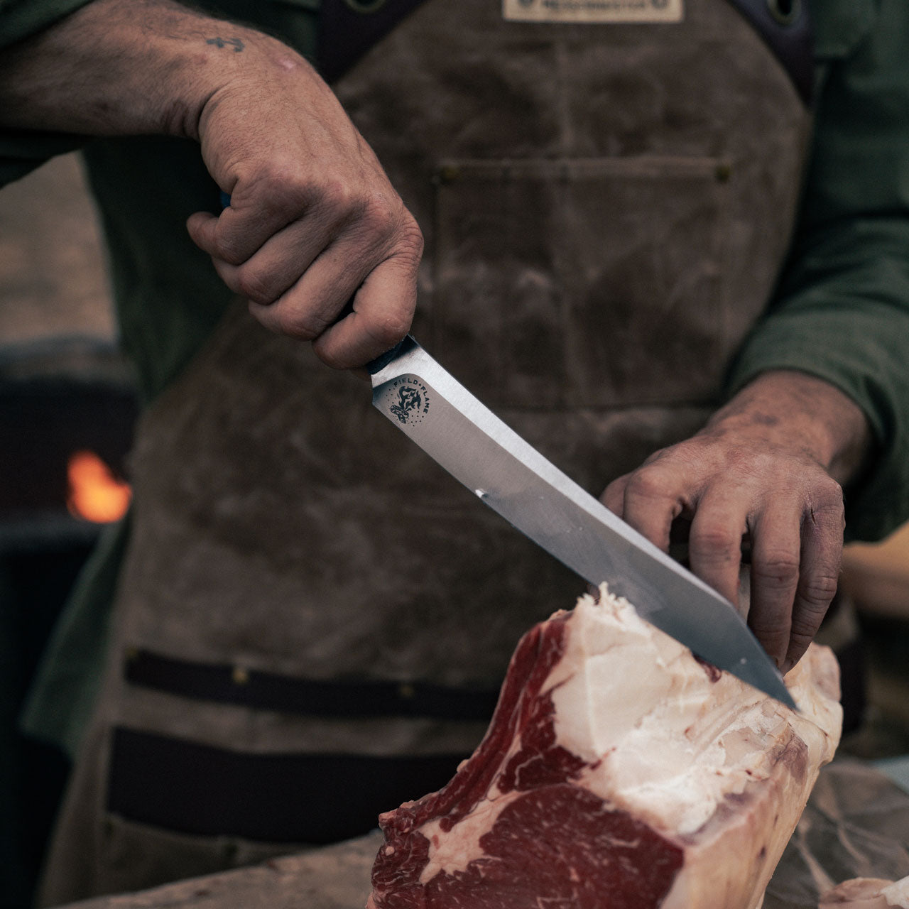 man wearing the brown leather apron while slicing meat outdoors