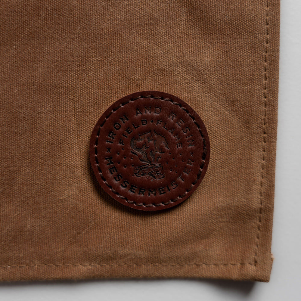 close up of field and flame leather logo on the brown apron