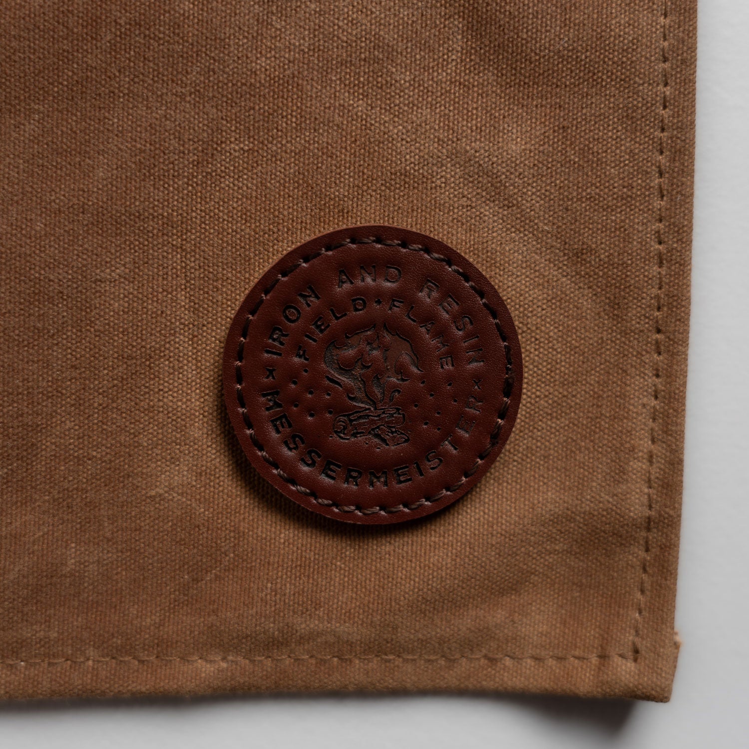 close up of field and flame leather logo on the brown apron