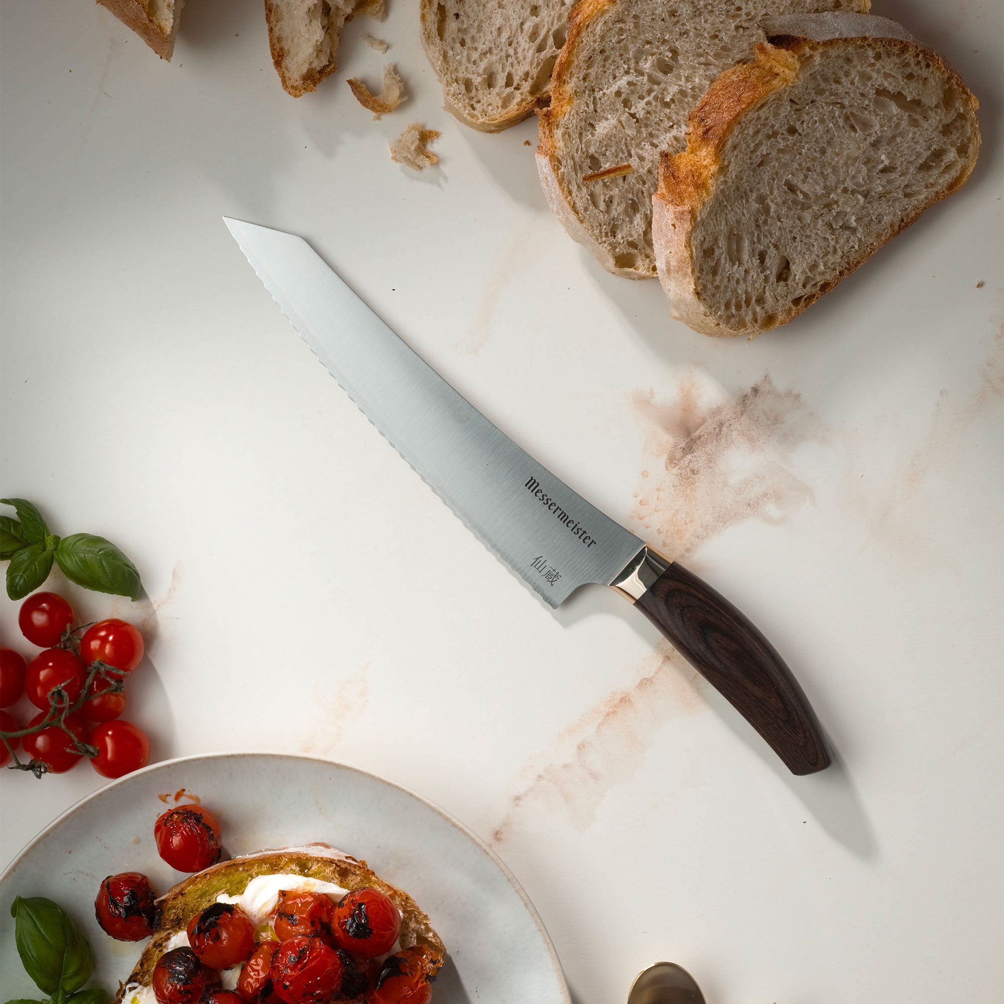 Messermeister Kawashima with sliced bread, burrata, tomatoes and basil on a marble surface