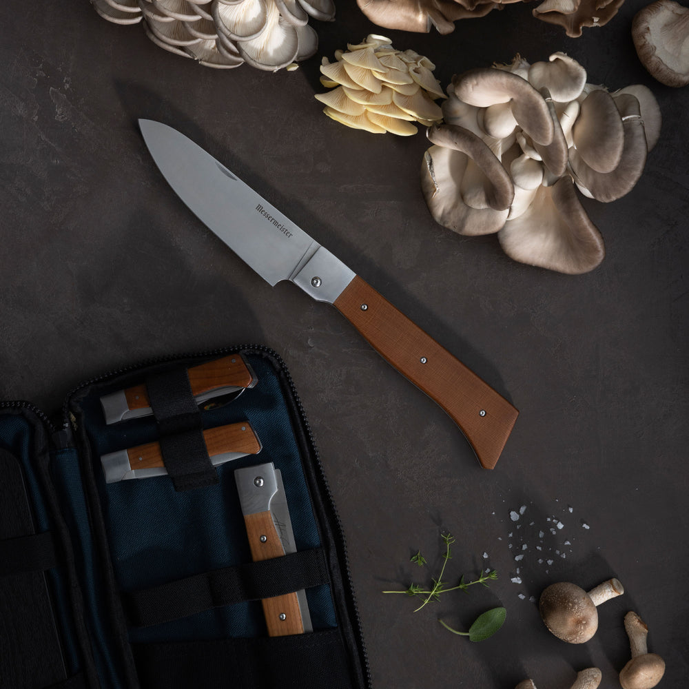 Messermeister Adventure Chef 6 Piece Set with brown handle on a dark surface with mushrooms