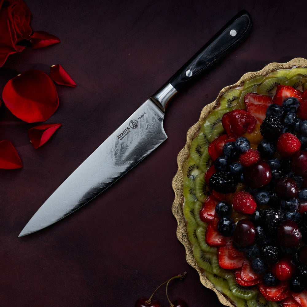 Messermeister Avanta Damascus Chef Knife with a fruit tart and rose petals on a dark red surface