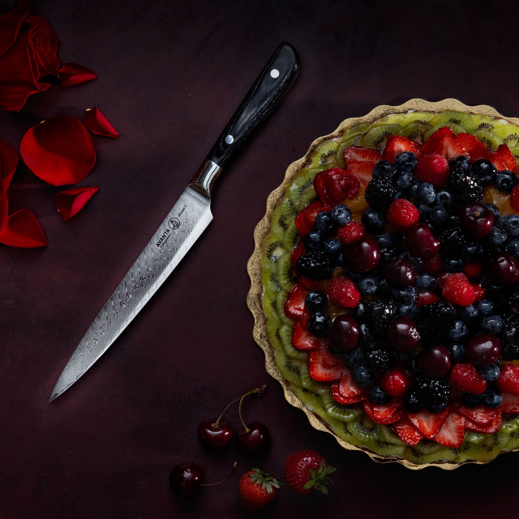 Berry tart with a Messermeister Avanta Damascus Slicing Knife on a dark red surface