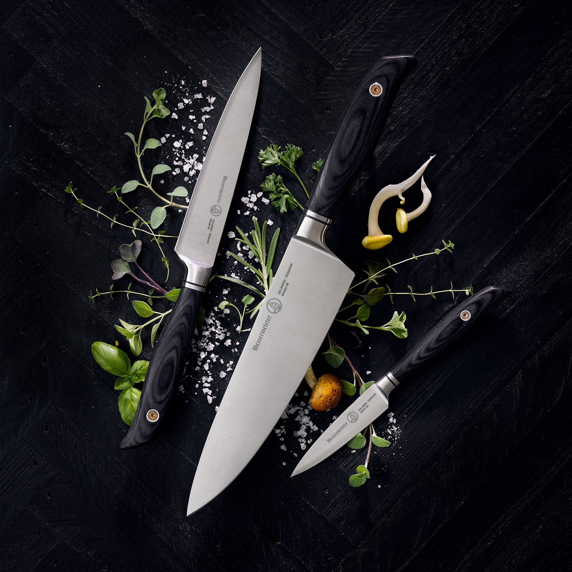 Messermeister Blacksmith Chef, Paring  and Utility knives on a dark surface with herbs and spices