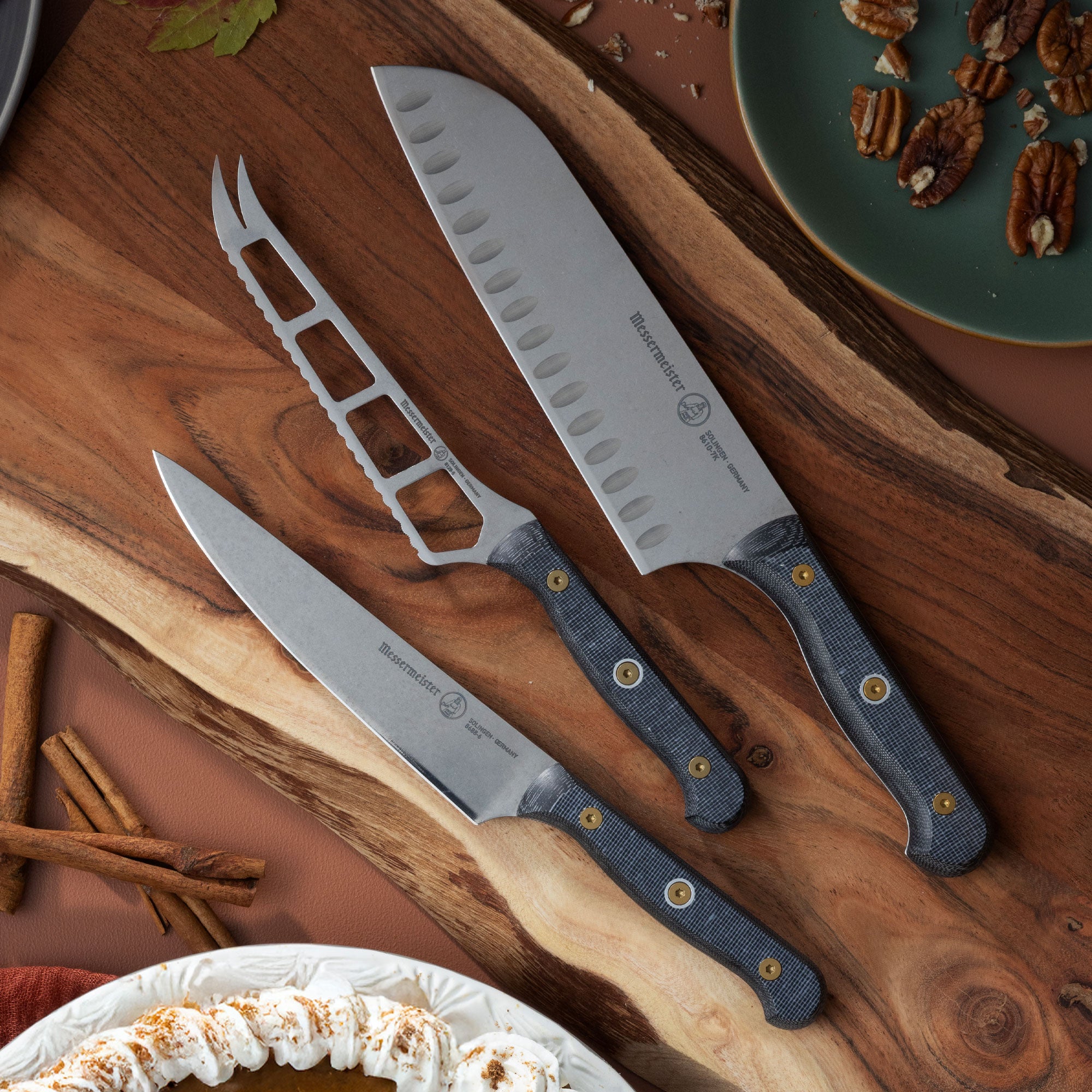 Messermeister Custom Cheese & Tomato Knife, Santoku and Utility Knives on Wood Cutting Board with Fall Setting
