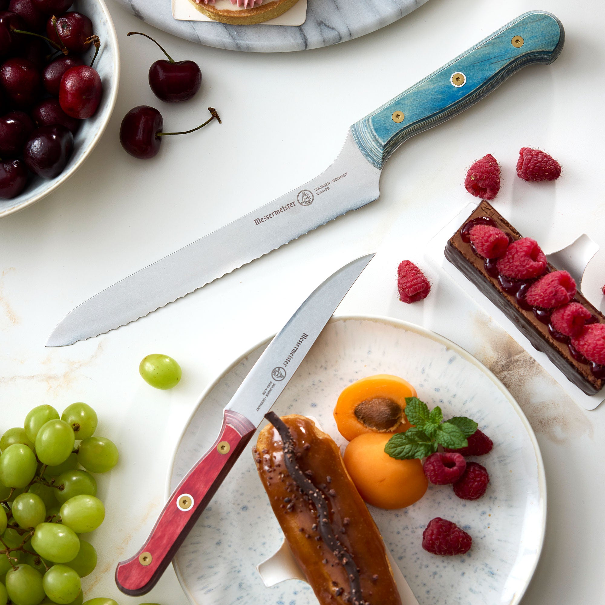 Messermeister Custom Blue Offset Scalloped Slicer Bread Knife with Custom Red Steak Knife in Mother's Day Pastry Setting with Fruit