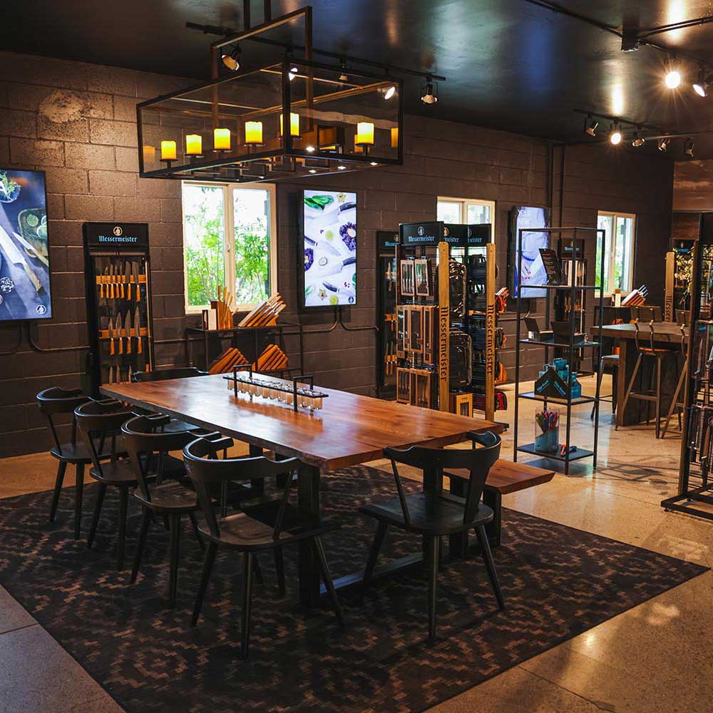 Modern restaurant interior with wooden tables and chairs, large windows, and decorative elements.