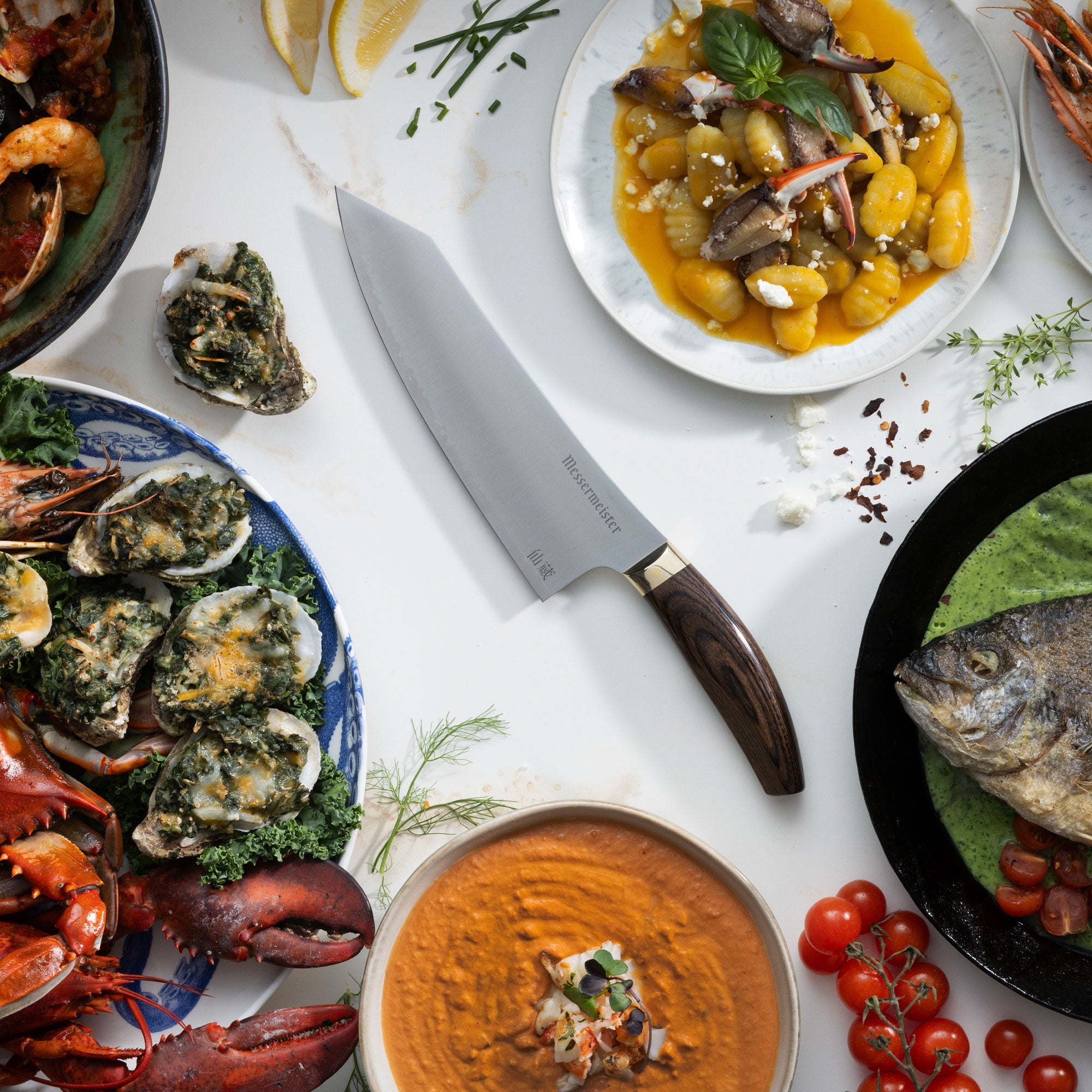 Messermeister Kawashima Chef Knife with Feast of Seven Fishes, hummus, tomatoes, and gnocchi on a white marble countertop