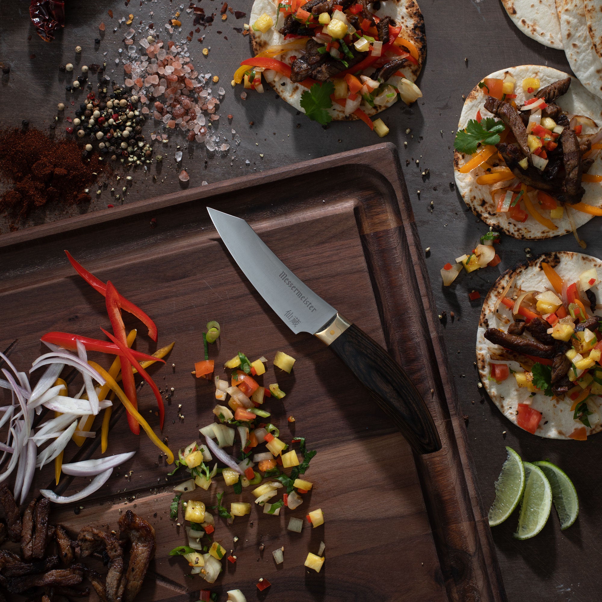 Messermeister Kawashima Paring Knife on a wooden cutting board with chopped vegetables and tortillas on a dark surface