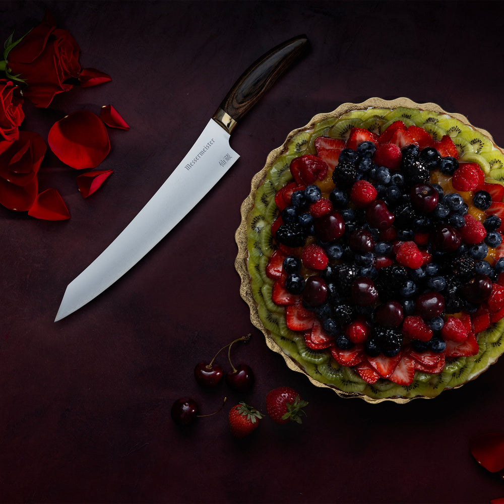Messermeister Kawashima Slicing Knife with a fruit tart, cherries, strawberries and rose petals on a dark red surface