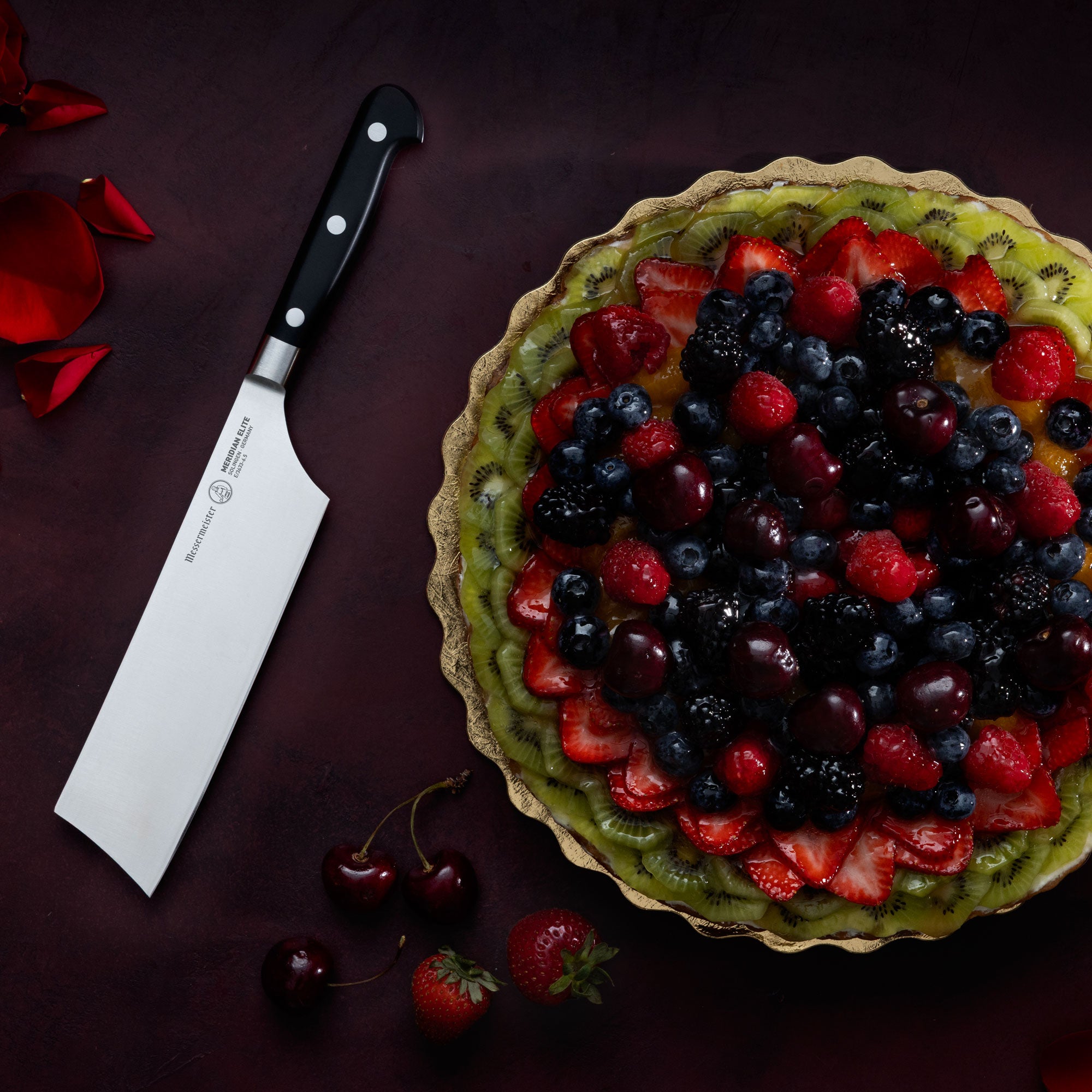 Messermeister Meridian Nakiri on Dark Background with Fruit Tart and roses