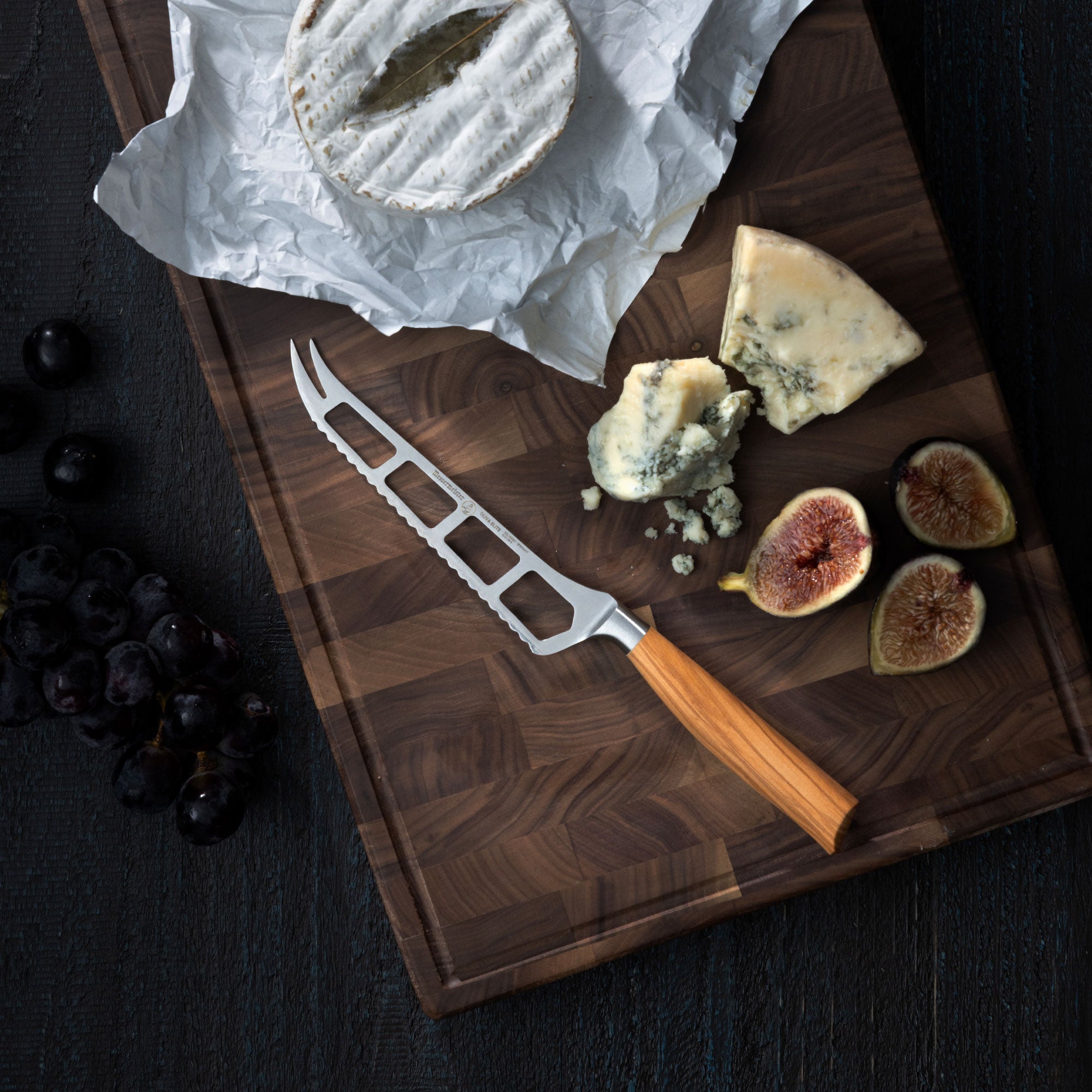 Cheese and figs on a wooden board with a Messermeister Oliva Elite Cheese and Tomato knife