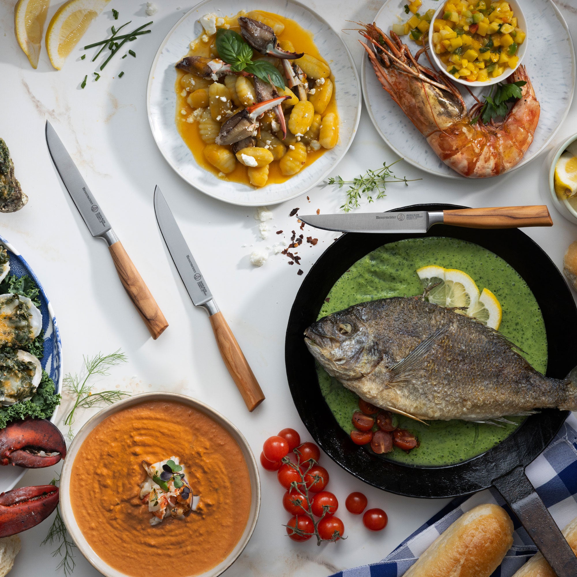 Assorted seafood dishes on a table with various garnishes and Messermeister Oliva Steak Knives