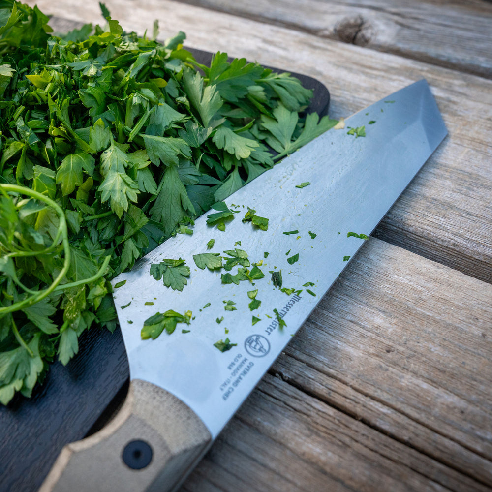 Messermeister Overland Camp Knife with chopped parsley on the Adventure Chef Folding Cutting Board on a wooden surface