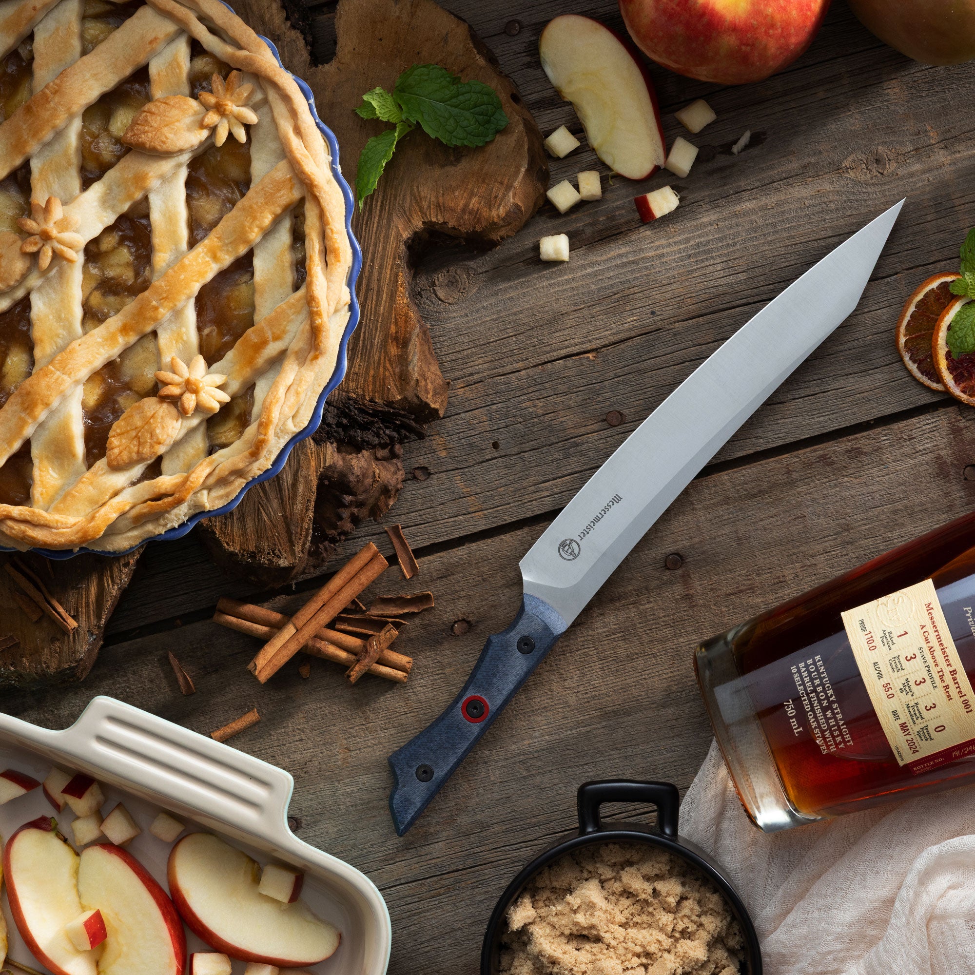 Messermeister Overland Chef Field and Flame Slicer pictured with Apple Pie and Bourbon and Fresh Apples on a Wooden Surface.