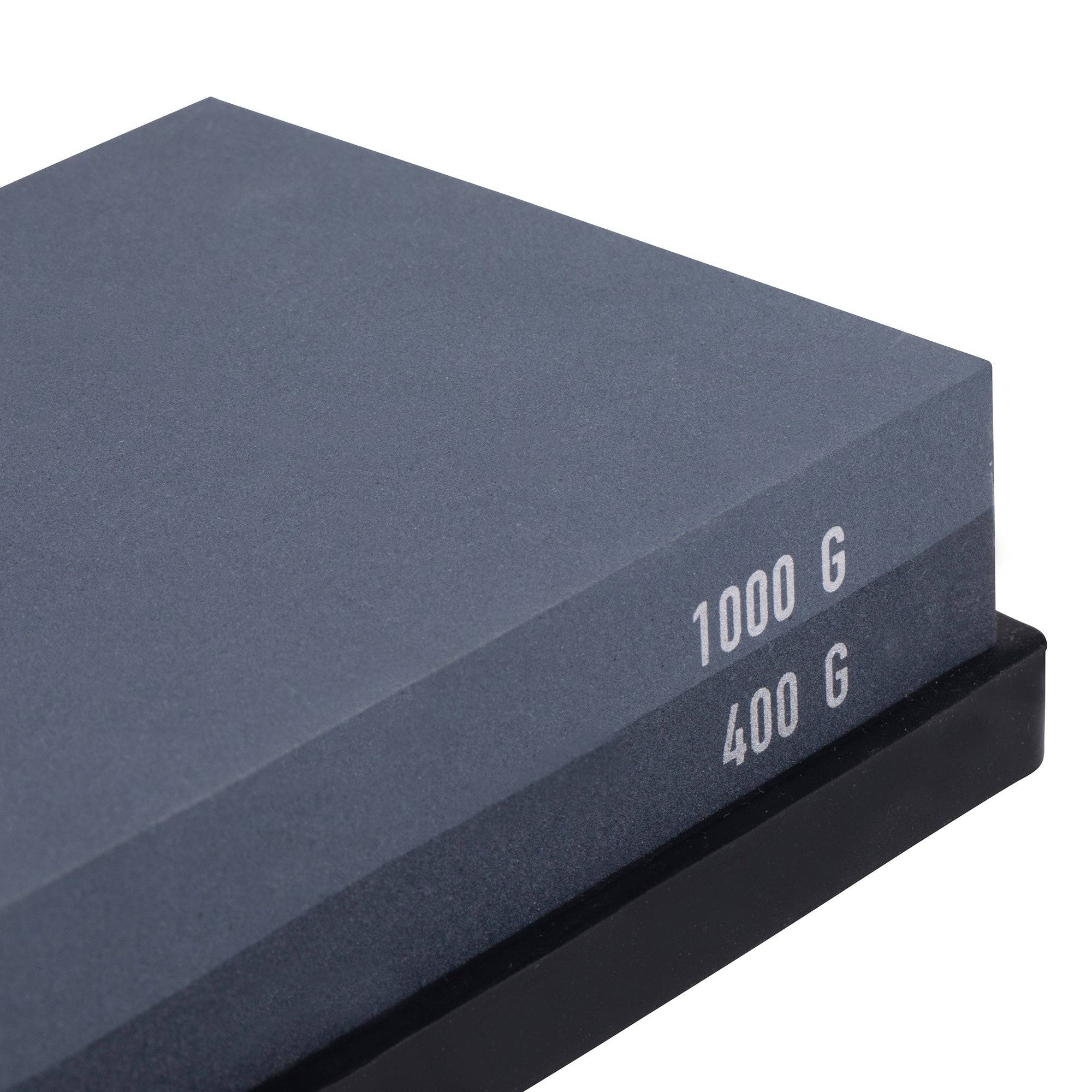 Messermeister 400 & 1000 grit Restoration Stone shows the right corner/edge. The top layer is gray with silver "1000 G" printed on the edge. Bottom layer is black with silver "400 G" printed on edge. The item sits in a black silicone base.