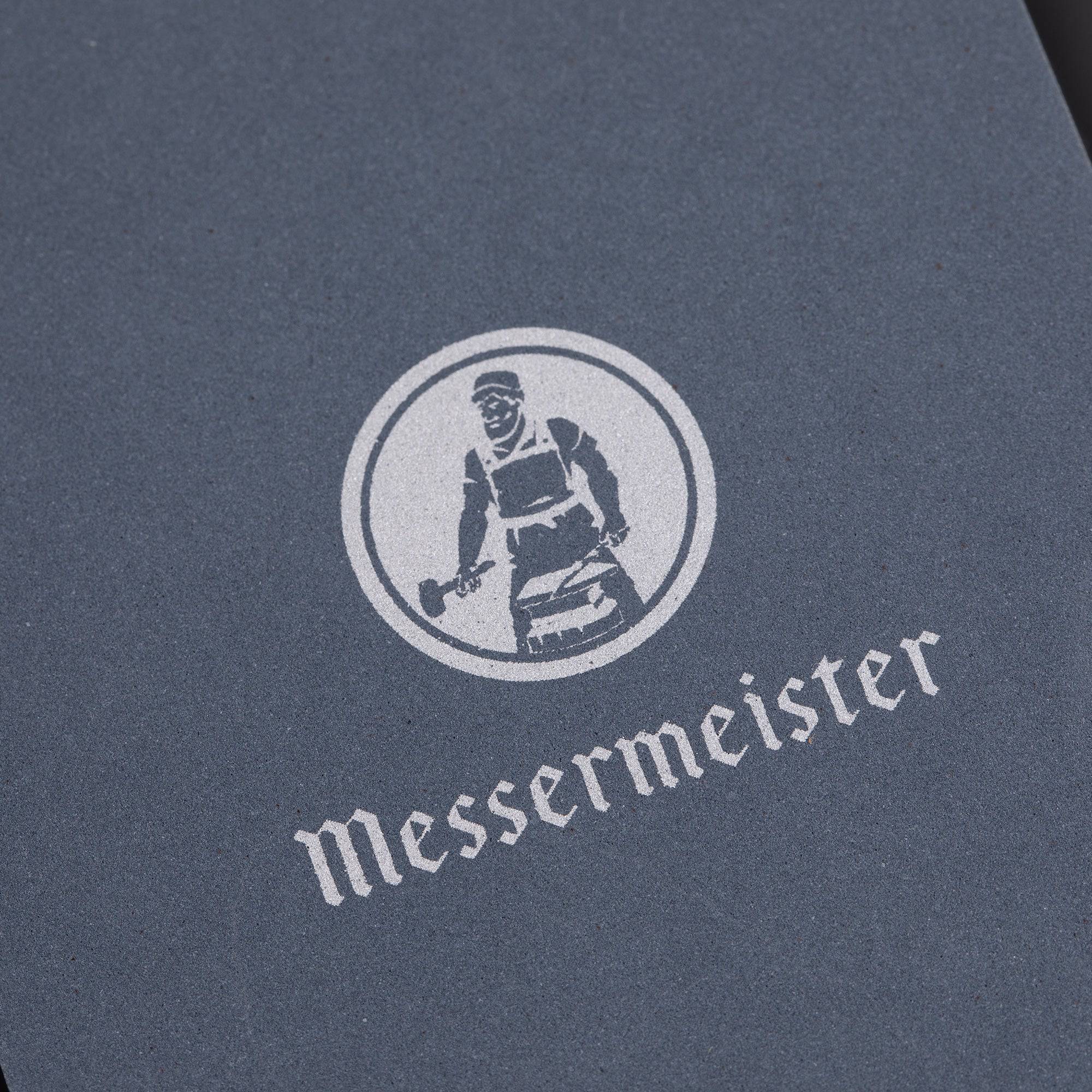 Messermeister 400 & 1000 grit Restoration Stone shows a close up of top gray layer of the stone with "Messermeister" name and logo in silver.