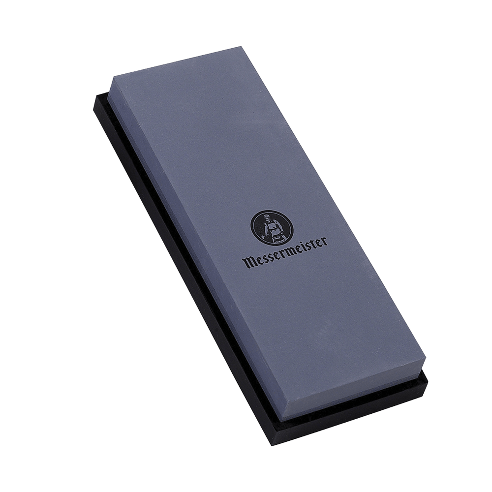 Messermeister 400 & 1000 grit Restoration Stone  is a dual sided rectangle 8" x 3" x 1". The top layer is gray with black "Messermeister" logo.  Bottom layer is black. The item sits in a rectangular black silicone base. Image tilted up and to the left.