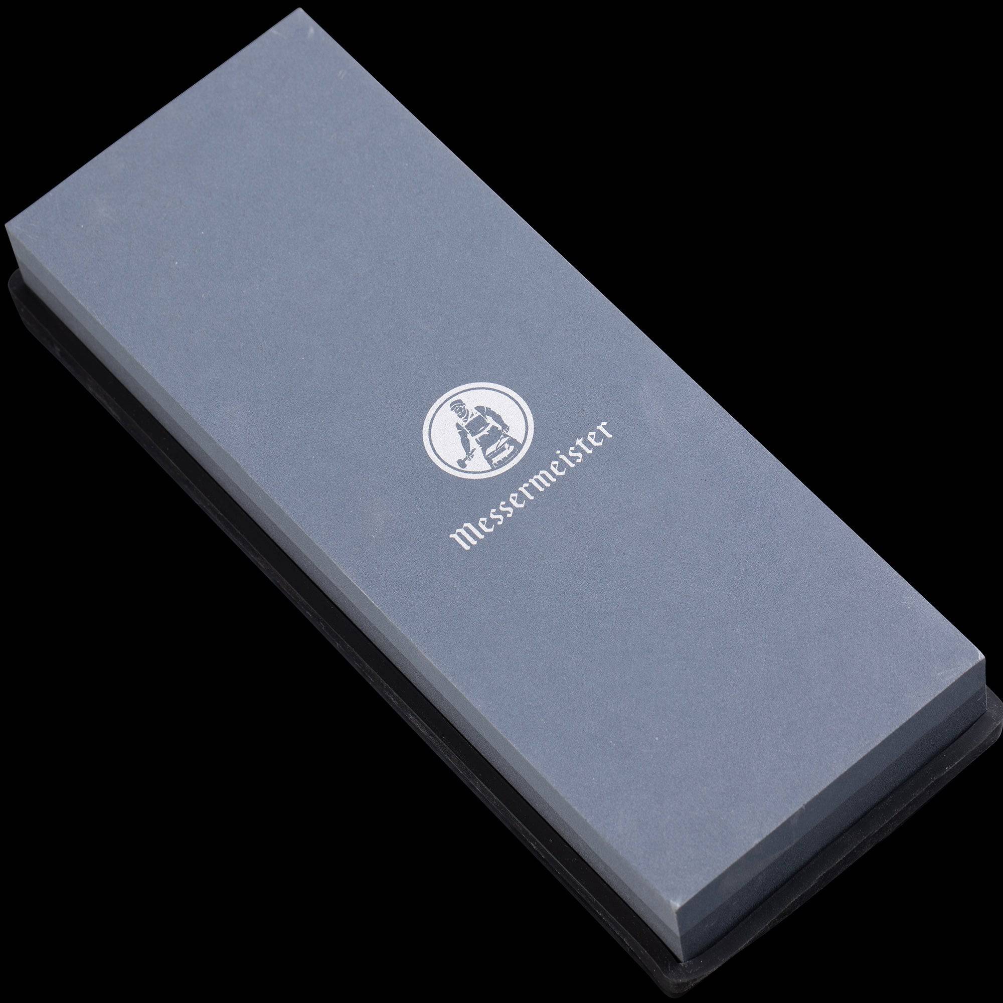 Messermeister 400 & 1000 grit Restoration Stone is a dual sided rectangle. The top layer is gray with silver "Messermeister" logo.  Bottom layer is black. The item sits in a rectangular black silicone base. Image tilted with the top towards the upper left.