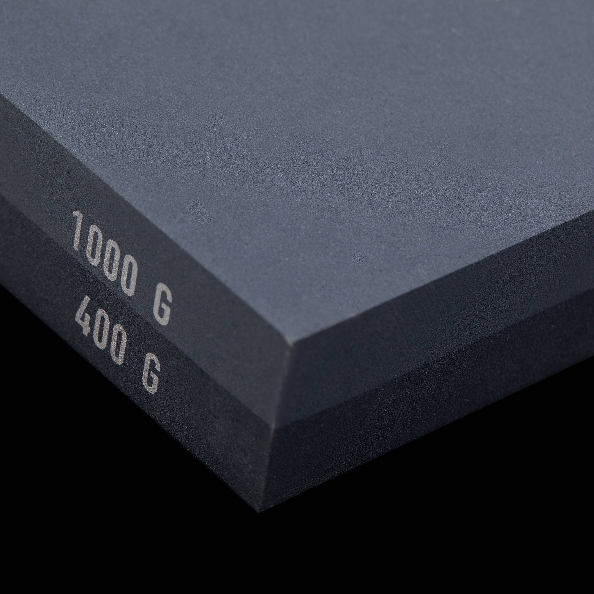 Messermeister 400 & 1000 grit Restoration Stone shows a close up of the corner/edge. The top layer is gray with silver "1000 G" printed on the edge. Bottom layer is black with silver "400 G" printed on edge.
