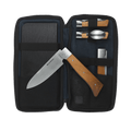 Messermeister Adventure Chef Maple Summit 6 Piece set showing the 6 inch folding Chef's Knife removed and laying on top of the open zippered carrying case with the folding utensil, folding peeler and parer, folding fillet knife and faux wood cutting board tucked inside.
