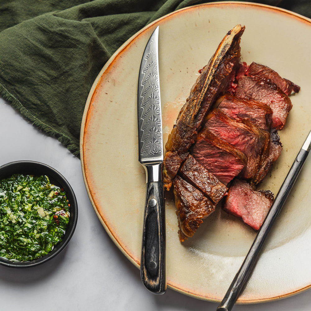 Messermeister Avanta Damascus steak knife placed next to cooked steak on plate