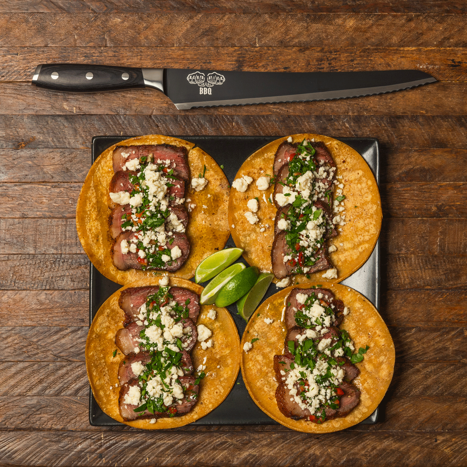 Messermeister Avanta Kendrick scalloped brisket BBQ knife next to four brisket tacos on black plate