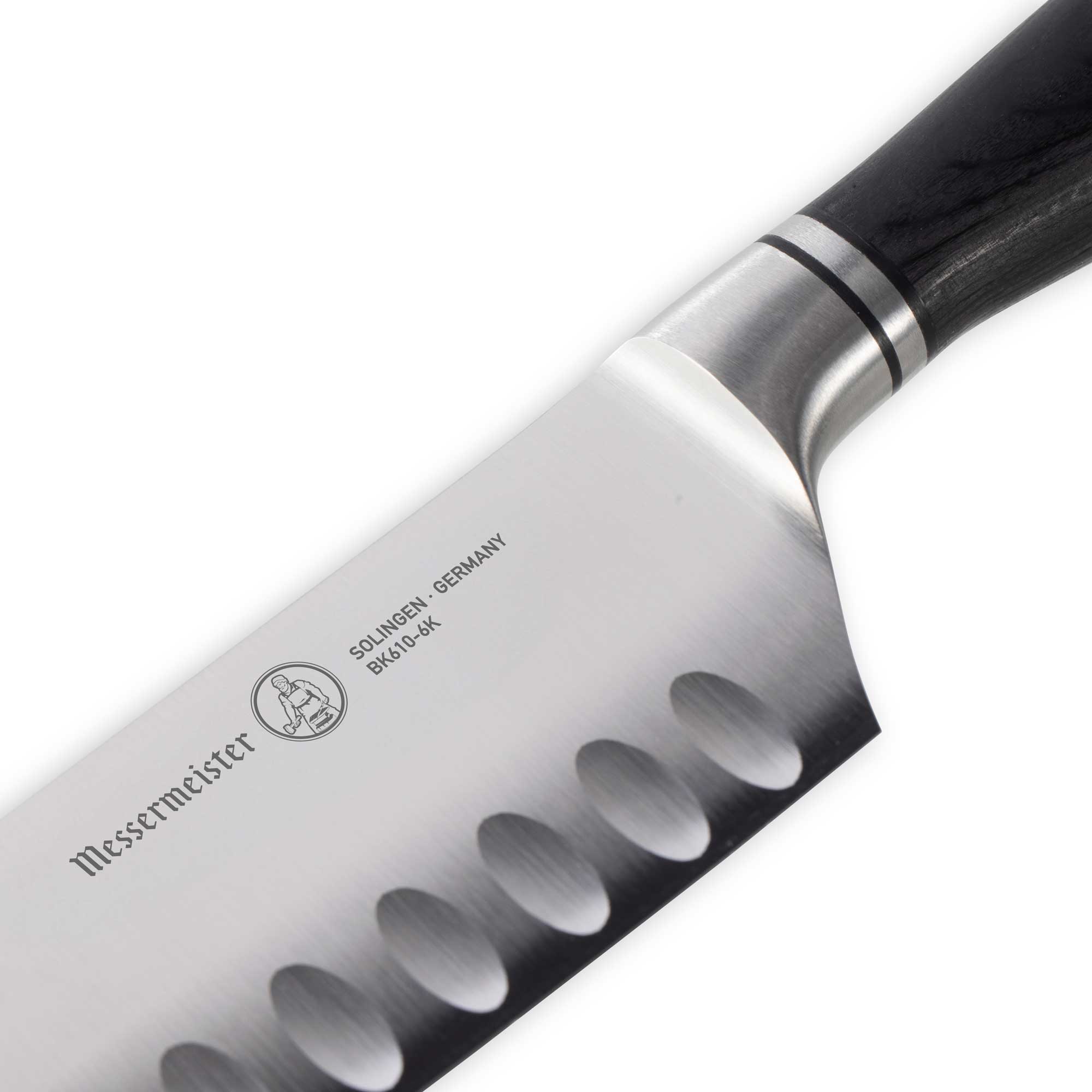 Close-up of the Messermeister logo engraved on the Blacksmith 6.5-Inch Kullens Santoku Knife blade, highlighting the hand-forged hammered finish and premium craftsmanship details