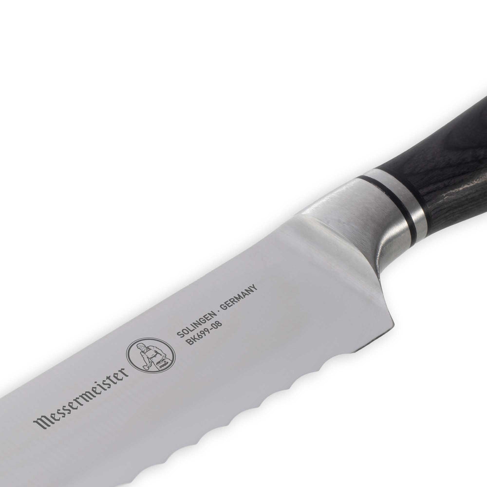Messermeister Blacksmith Scalloped Slicing Knife 8.5 inch with stainless steel blade and ebony pakkawood handle close up on knife logo
