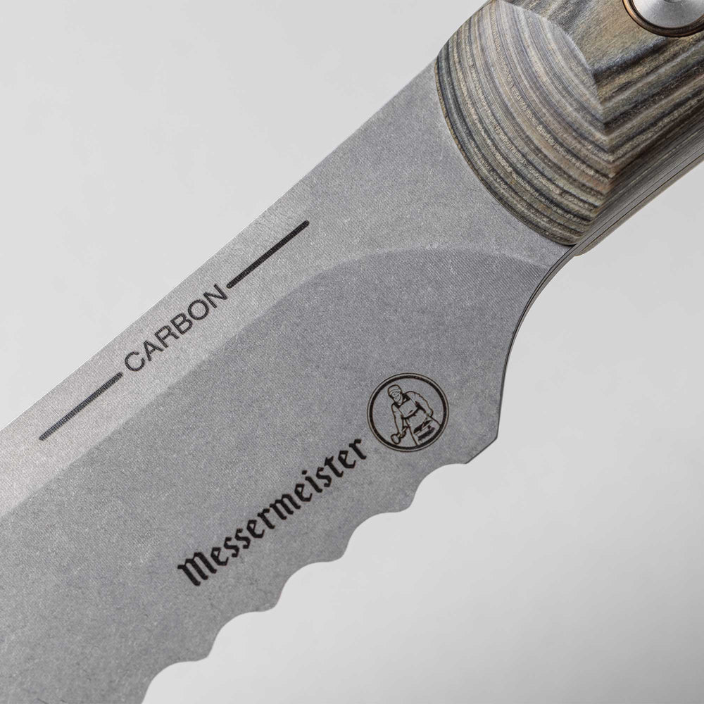 A close up view of the 9 inch Carbon Bread Knife serrated heel and logo