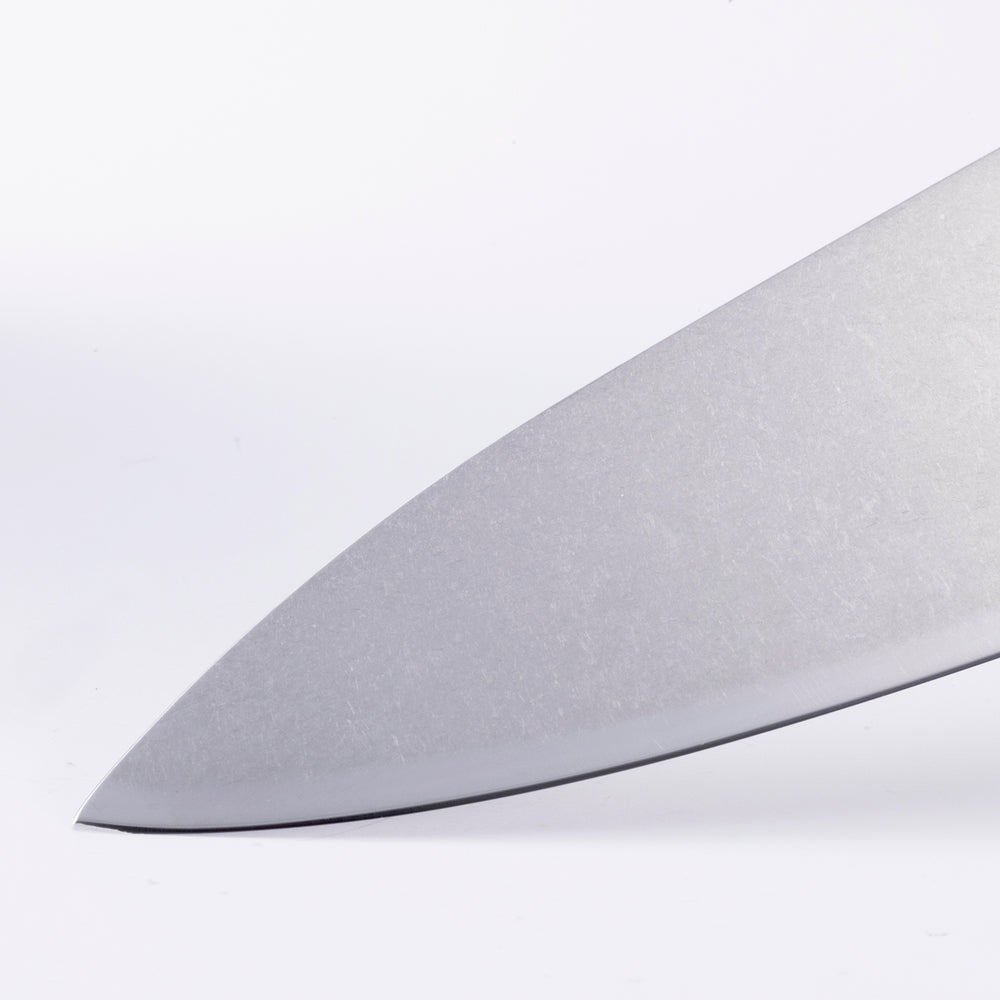 Detail of custom chef knife tip showing precision edge and pointed stainless steel blade