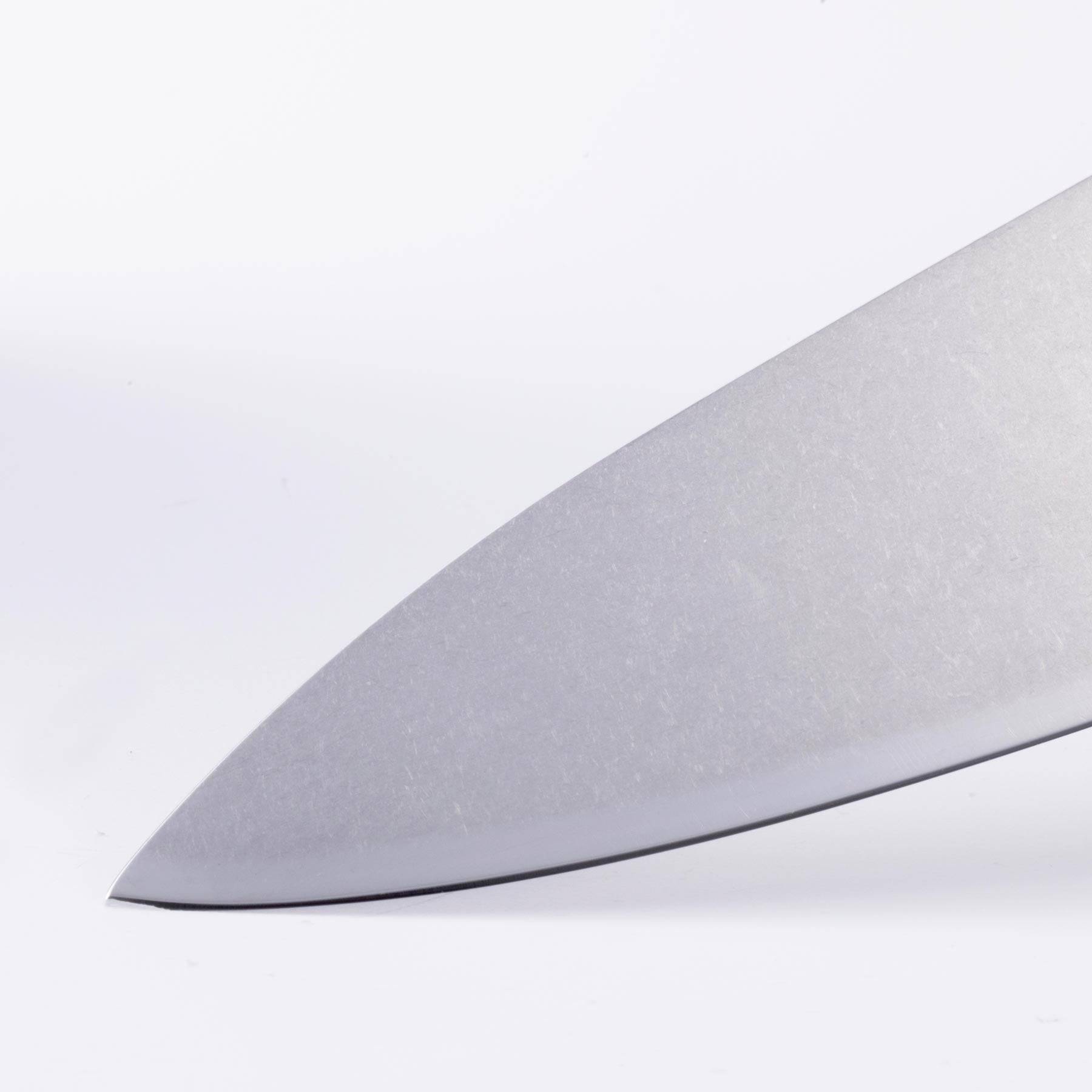 Close-up of the sharp tip of an 8-inch Messermeister Custom Red chef’s knife, showing the fine tapered point of the polished stainless steel blade