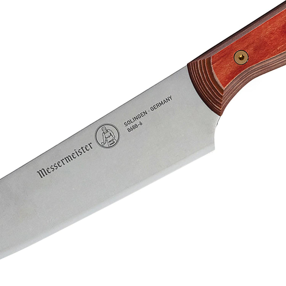 Close-up of the Messermeister Custom Red utility knife handle, highlighting the embossed logo detail on the red ergonomic grip against a polished stainless steel blade