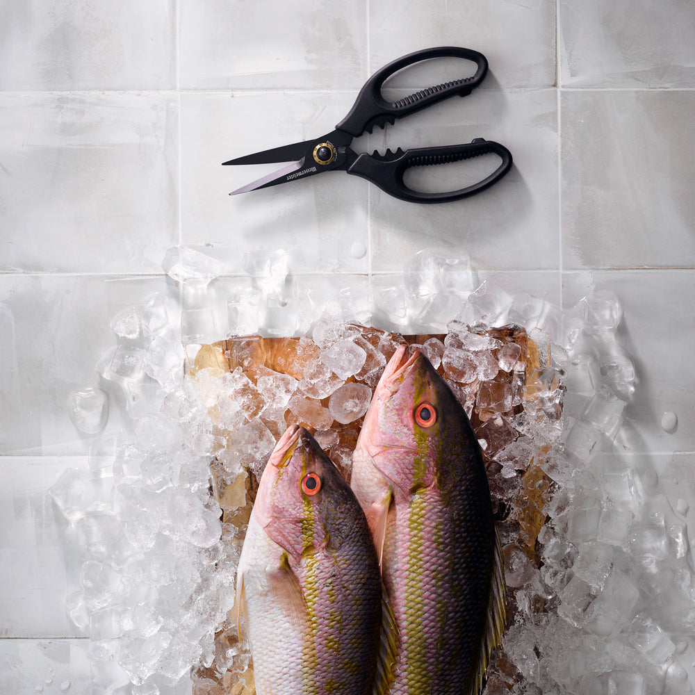 Esther Choi 7-inch push button take-apart precision shears displayed beside fresh fish on ice, featuring stainless steel precision blades and ergonomic handles for seafood prep and detailed kitchen cutting tasks