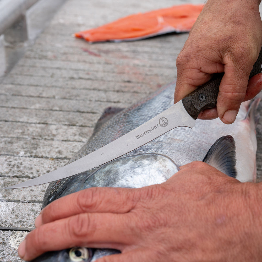 photo of person using the overland filet knife slicing a fish on a deck
