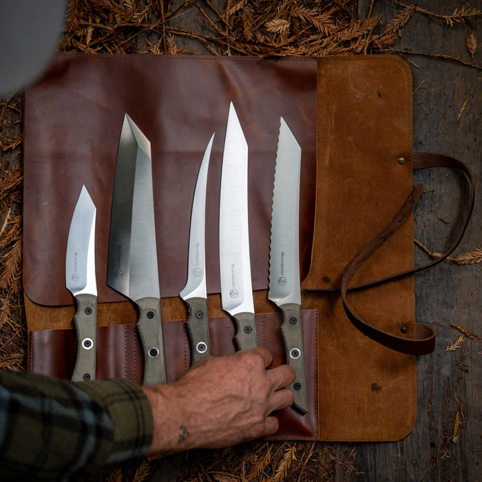 Messermeister Overland Chef Leather Knife Roll Set open and showcasing scalloped slicer, slicer, filet knife, chef knife, and utility knife