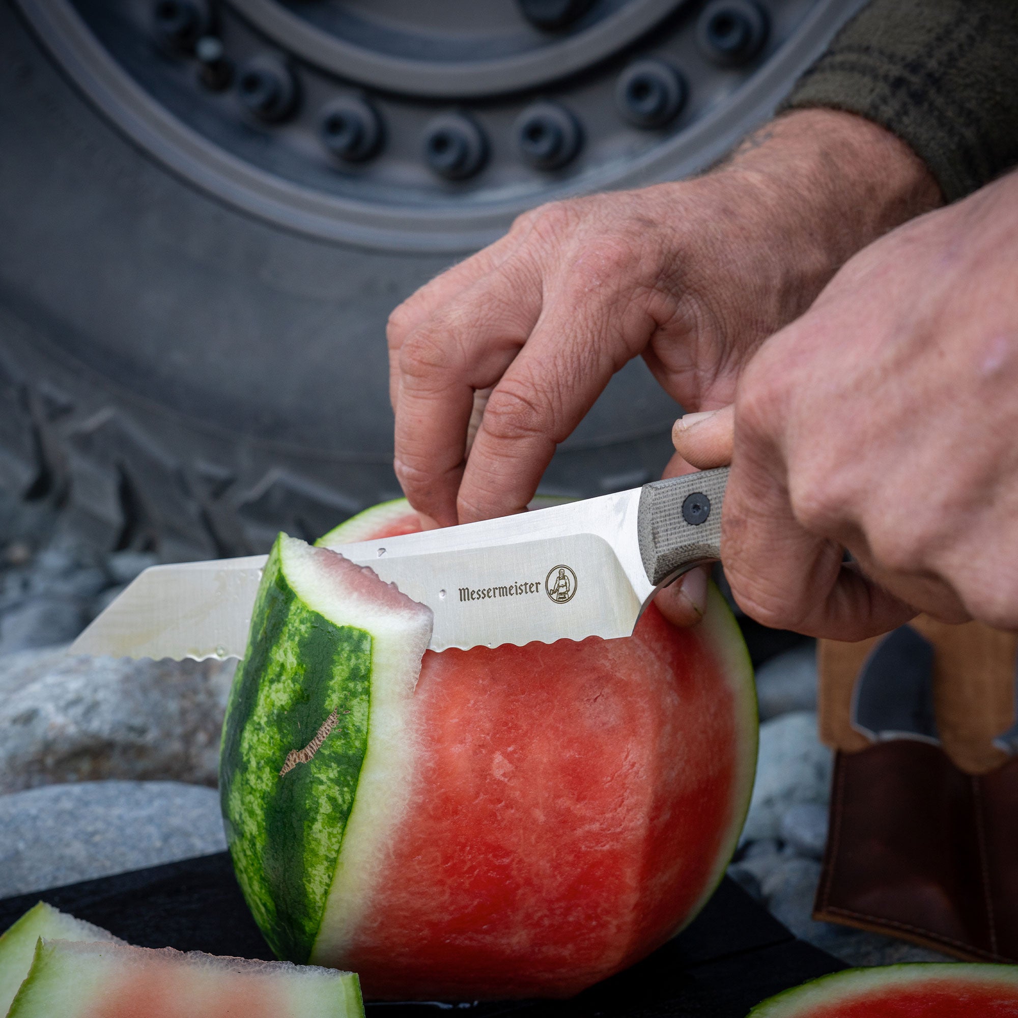 overland scalloped slicer cutting a watermelon in front of a tire