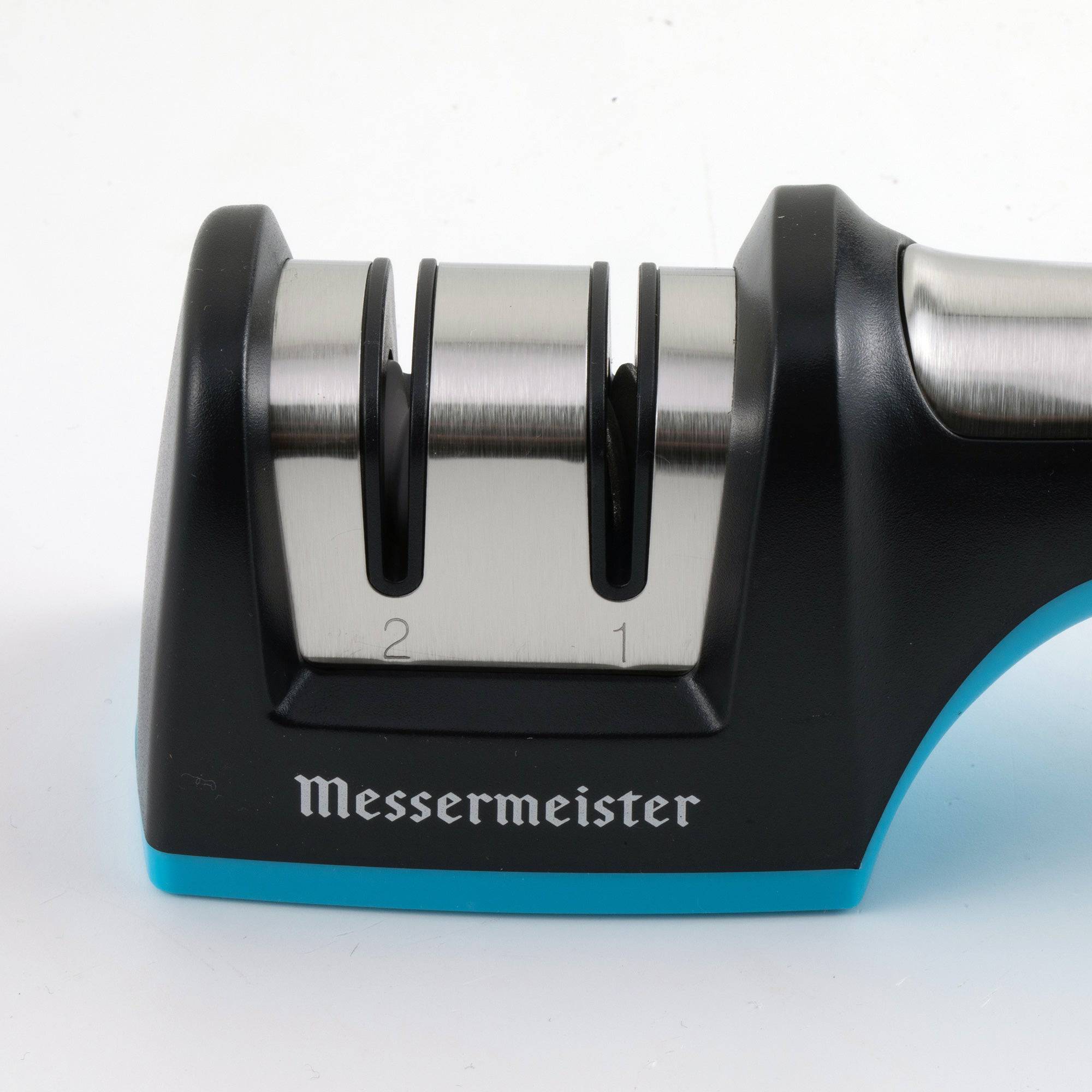 A close up of the sharpening mechanics on the Messermeister Pull Through Sharpening slots. The slot on the left has a "2" engraved under and the slot on the right has a "1". The word "Messermeister" is printed in white on the black surrounding layer.