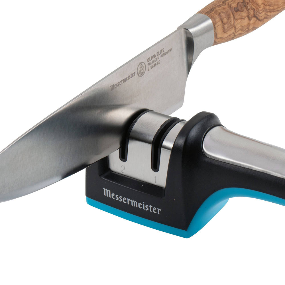 Messermeister Pull Through Knife Sharpener. A close up of a wood handled knife with blade inside the left side sharpening slot.