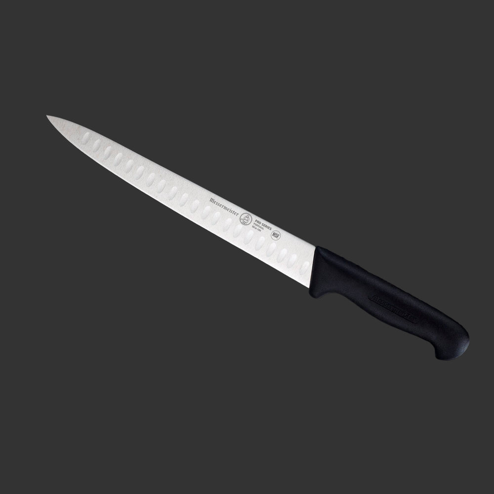 Messermeister Pro Series 10-inch kullens carving knife angled to highlight granton-edge stainless steel blade and ergonomic non-slip black polyfibre handle for smooth carving