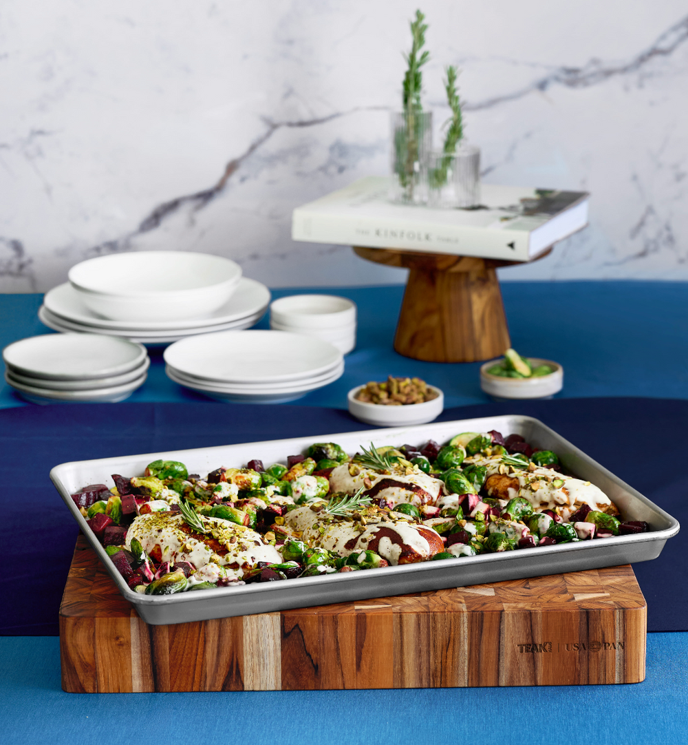 Teakhaus Board to Pan cutting board with cooked chicken and vegetables in the built-in pan, ready for serving.