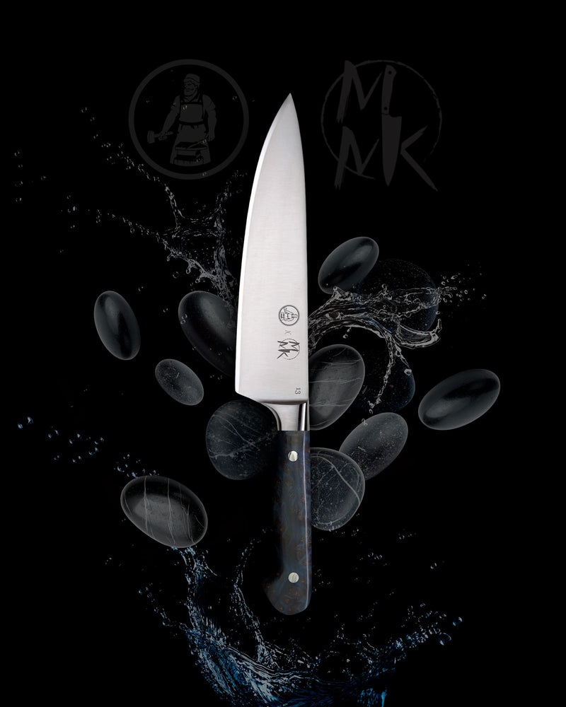 A professional chef's knife with a silver stainless steel blade and a dark, marbled handle, presented against a black background with water splash effects and floating dark stones. The brand logo 'MK' is visible on the blade and in the background.