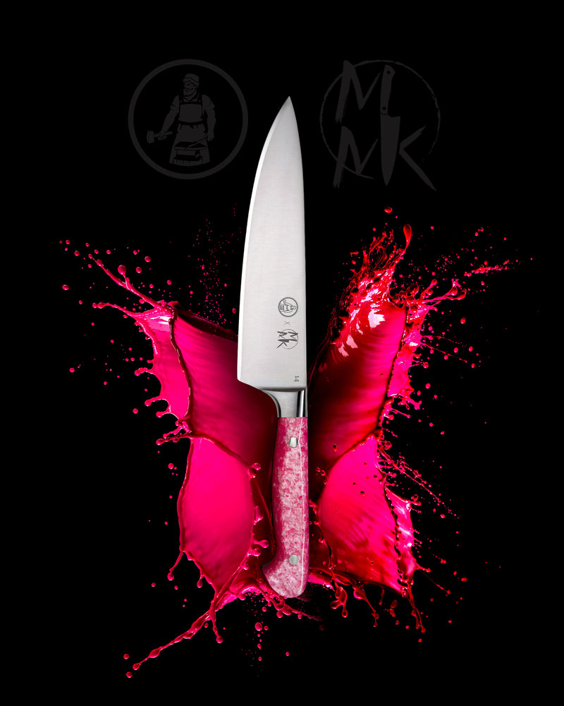 A professional chef's knife with a silver blade and a textured pink handle, positioned vertically over a vibrant hot pink liquid splash on a solid black background. The M&M Kitchen logo is visible on the blade and as a watermark in the background.
